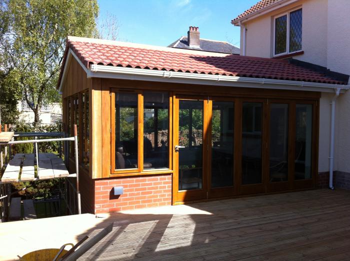 A completed property extension with timber doors and a tiled roof